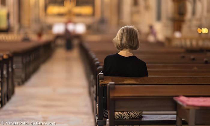 Eine Frau sitzt alleine in der Kirche