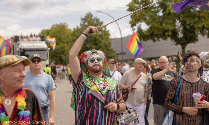Menschen in bunter Kleidung und mit Regenbogenfahnen