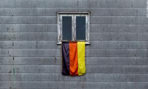 Deutschlandfahne vor grauer Hauswand.