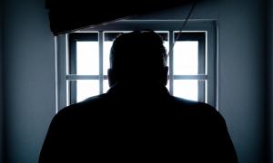 Mann vor einem vergitterten Fenster