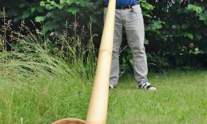 Alphornbauer Thomas Rupp spielt in seinem Garten in Seeg im Allgäu