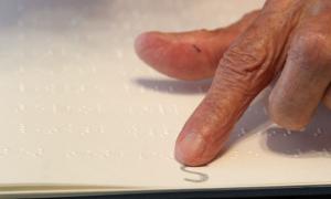 Ein Finger tastet Brailleschrift ab