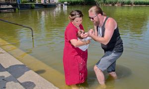 Pfarrer Andy Gatz tauft ein Kind im Kemptener Bachtelweiher