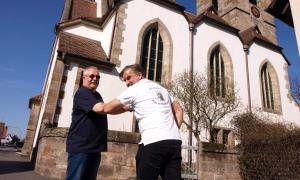 Wolfgang Victor und Pfarrer Christian Schmidt beim coronakonformen Gruß vor der Egidienkirche Eltersdorf