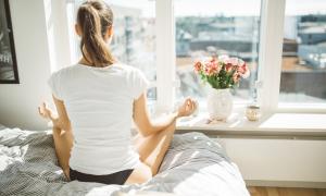 Frau meditiert auf dem Bett
