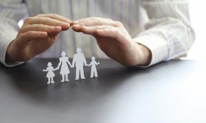 Zwei Hände, schützend über eine Familie gehalten