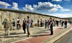 Menschen stehen vor der Berliner Mauer