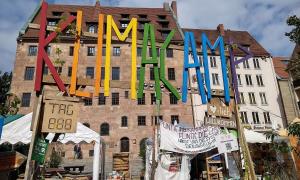 Ein Bild des Klimacamps in Nürnberg. Man sieht ein Eingangstor mit der Aufschrift "Klimacamp" und aufgebaute Zelte,