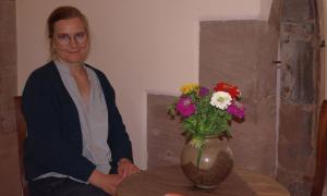 Melanie Stummhöfer sitzt an einem Tisch mit einer Blumenvase.