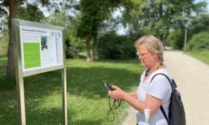 Andrea Hofmann auf dem Interreligiösen Weg in Bamberg vor einem Schild.