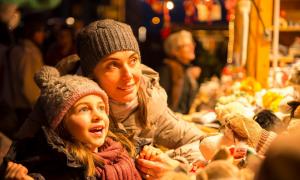 Eine Frau und ein Kind vor einem erleuchteten Weihnachtsmarktstand.