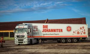 Ein großer Truck, der auf einem Hof steht. An der Seite steht "Die Johanniter", außerdem sieht man das Logo und Geschenke aufgedruckt