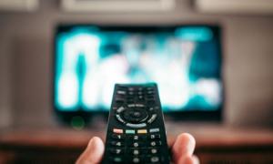Ein Fernseher unscharf im Hintergrund und vorne mittig eine Fernbedieung