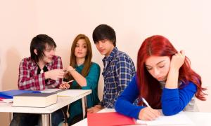 Drei Mitschüler*innen mobben eine Schülerin
