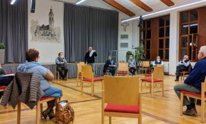 Menschen sitzen in einem Stuhlkreis.