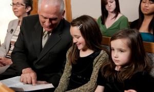 Ein alter Mann zeigt einem Mädchen im Gottesdienst eine Stelle in der Bibel
