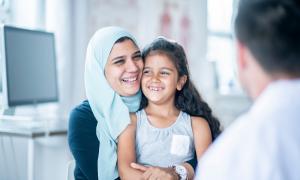 Eine Frau umarmt ein Mädchen, beide lachen