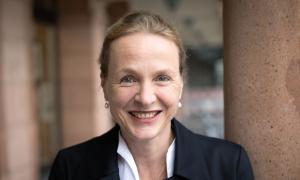 Eine Frau mit zurückgebundenen Haaren, sie lächelt