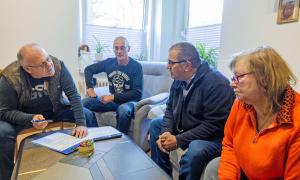 Mehrere Menschen sitzen um einen Wohnzimmertisch