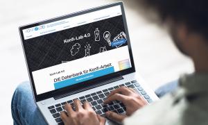Ein Mann hat einen geöffneten Laptop auf dem Schoß und tippt auf den Tasten
