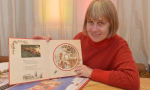 Eine Frau zeigt ein Buch mit Weihnachtsmotiven in die Kamera