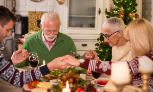 Eine Familie sitzt betend am Tisch