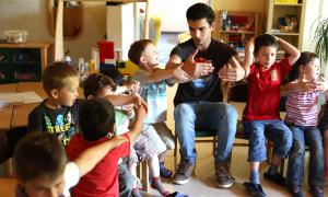 Ein Erzieher sitzt mit Kindern in einem Stuhlkreis