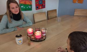 Eine Frau sitzt an einem Tisch mit Kerzen, ihr gegenüber ein Junge, den man nur von hinten sieht