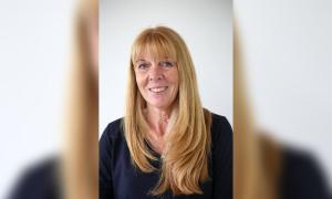 Porträtbild einer Frau mit rotblonden langen Haaren und Pony. Sie lächelt und trägt ein dunkelblaues Oberteil.