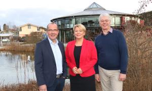 Zwei Männer und eine Frau stehen vor einem Teich