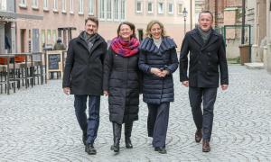 Zwei Männer und zwei Frauen in Winterkleidung in einer Fußgängerzone