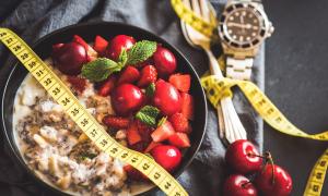 Eine Schale mit Müsli, eine goldene Uhr, Besteck und Kirschen
