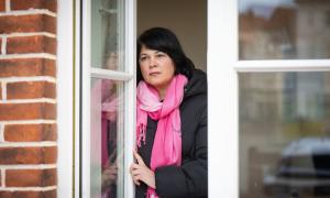 Eine Frau steht am Fester und schaut hinaus