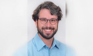 Ein Mann mit Brille und Vollbart, er lächelt