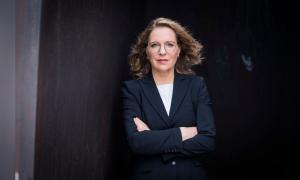 Eine Frau im dunklen Blazer, die Arme verschränkt