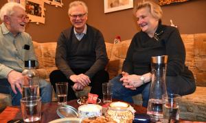 Drei Menschen sitzen an einem Wohnzimmertisch
