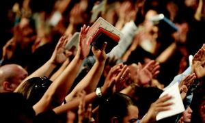 Menschen heben in einem Gottesdienst die Hände