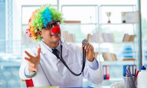 Ein Arzt sitzt verkleidet als Clown an seinem Schreibtisch.