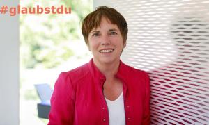 Eine Frau in rotem Jacket, dazu der Schriftzug "#glaubstdu"