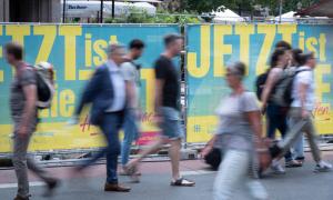 Menschen laufen vor Plakaten mit dem Kirchentags-Motto "Jetzt ist die Zeit"