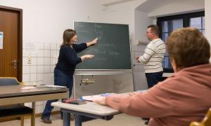 Menschen stehen an einer Tafel, auf der Worte auf Deutsch stehen