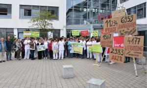 Menschen mit Schildern vor einer Klinik