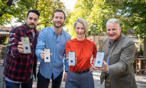 Vier Personen halten ihr Handy mit der App "SafeNow" in die Kamera.