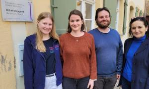 Vier Personen stehen nebeneinander und lächeln.