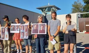 Menschen mit Bildern von Menschen vor einem Gefängnis