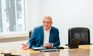 Ein Mann im blauen Anzug sitzt an einem Schreibtisch