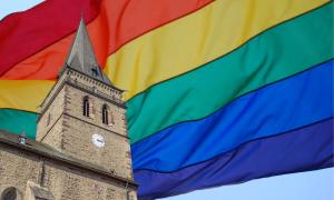 Eine Kirche vor einer Regenbogenfahne
