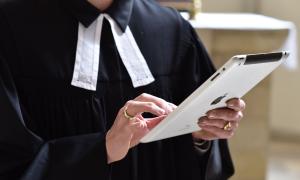 Eine Pfarrerin im Talar mit iPad in der Hand