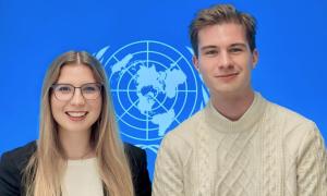 Eine junge Frau und ein junger Mann vor dem UN-Logo