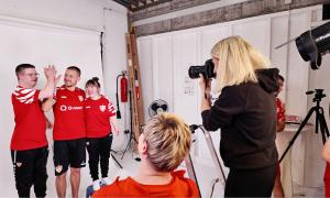 Eine Frau fotografiert drei Menschen in roten Hemden